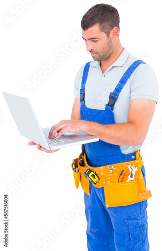 Handyman in overalls using laptop