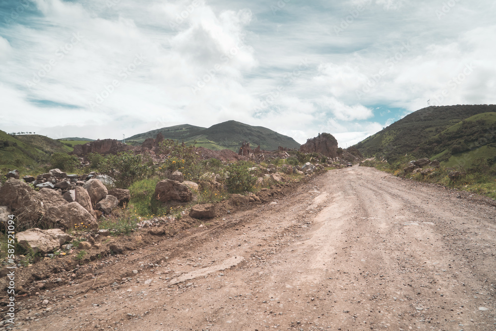 unpaved, dirt road on remote mountain province in developing nation, hard packed earth with large stones and boulders on the side of the passage for 4x4 vehicles and transport trucks