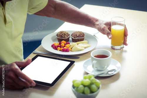 Man using digital tablet while having breakfast