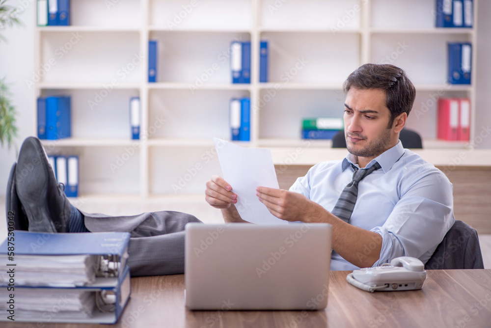Young male employee unhappy with excessive work in the office Young male employee unhappy with excessive work in the office