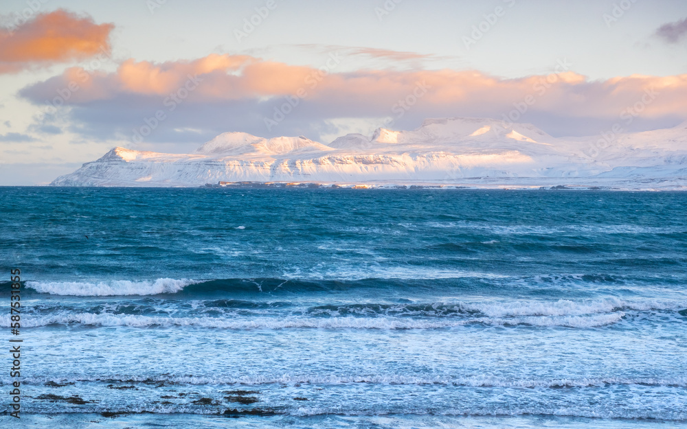 Snowy Mountains at Winter, Sunrise with Fluffy Clouds and Stormy Sea in Iceland. Landscape in North Europe Country. Atlantic Ocean Coast and Icelandic Fjords. Snowy Mountains at Winter, Sunrise with Fluffy Clouds and Stormy Sea in Iceland. Landscape in North Europe Country. Atlantic Ocean Coast and Icelandic Fjords.
