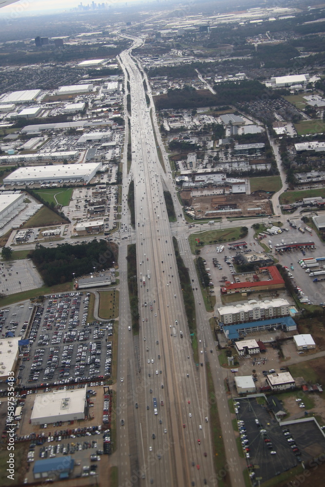 A bird's eye view of a busy highway reveals a winding ribbon of concrete and asphalt, snaking its way through a sea of cars and trucks.