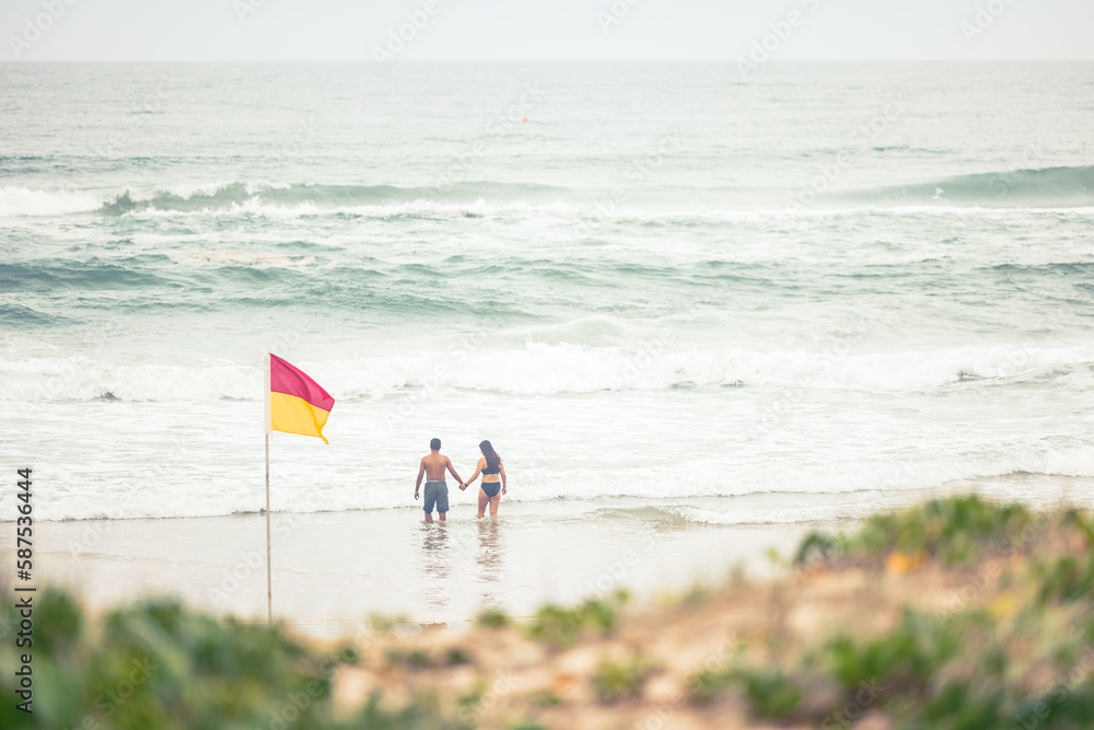 Obraz premium Man and woman couple holding hands in the water at Main Beach, Surfers Paradise Australia