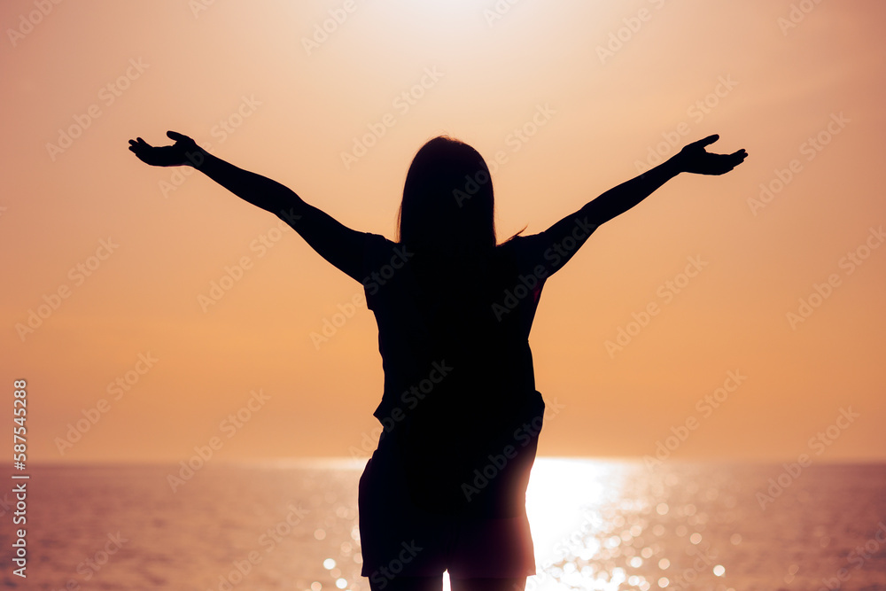 Silhouette of a Woman With her Arms Outstretched in Sunset View. Carefree girl feeling excitement and positivity  
