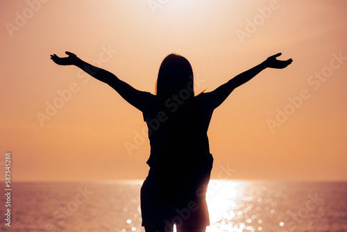 Silhouette of a Woman With her Arms Outstretched in Sunset View. Carefree girl feeling excitement and positivity    © nicoletaionescu