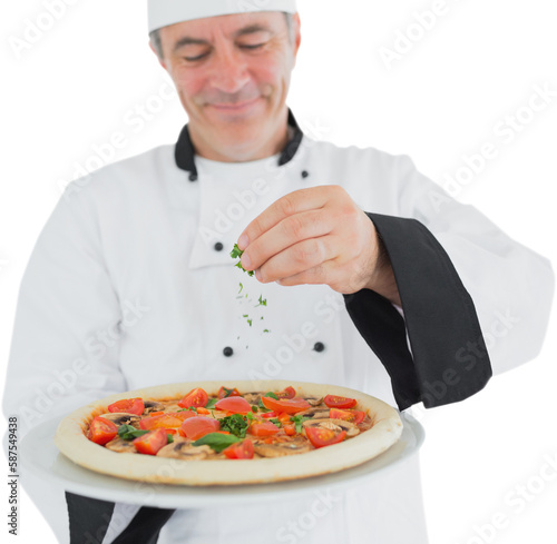 Portrait of a chef holding a pizza and adding herbs