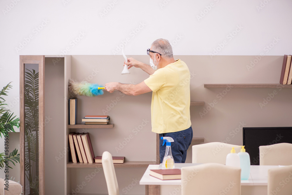 Fototapeta premium Old man doing housework at home