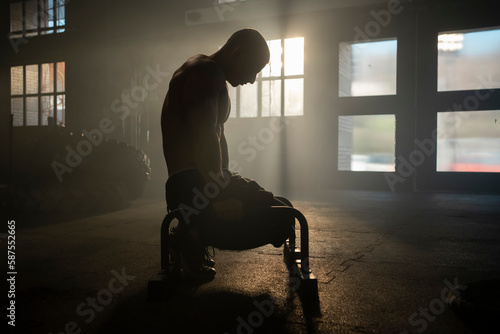 Fotografie Man with muscular body doing calisthenics training on parallettes bar on floor a