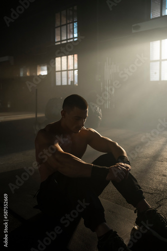 Quadro su tela Sportsman with well trained body sitting on the floor in fitness gym
