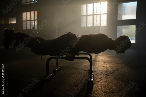 Fotografie Strong bodybuilder man doing calisthenics planche workout on parallel bars
