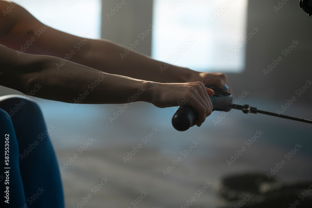 Cropped view of a female using a rowing machine during cross fit training. Female athlete exercising intensely in the gym