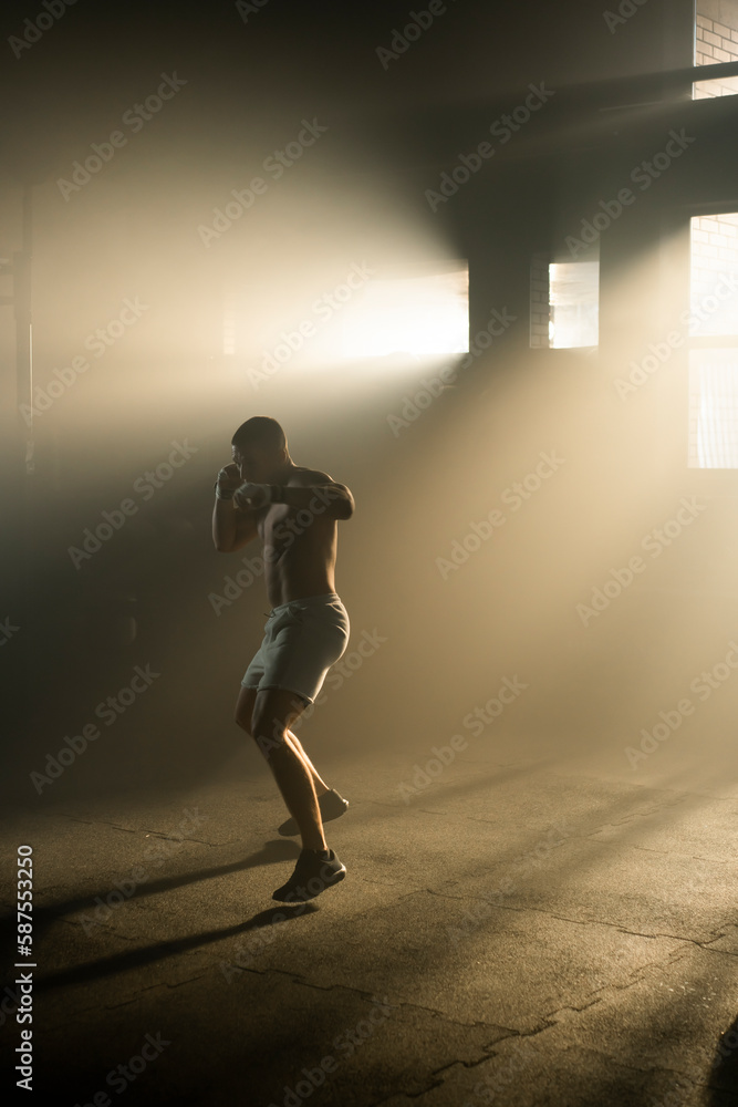Full shot of a strong boxing man sweating and doing air punching training in the box gym