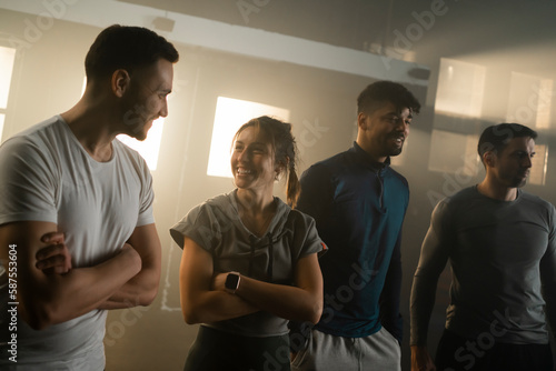 Healthy group of four friends in gym enjoying conversation, smiling and discussing fitness practice and chatting in studio