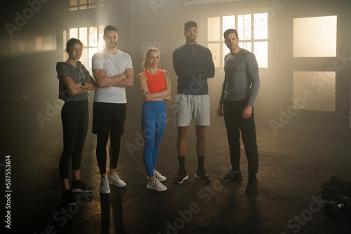 A group of young men and women standing in gym  posing at camera  looking strong and confident