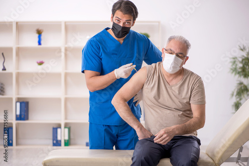 Old male patient visiting young male doctor in vaccination conce © Elnur
