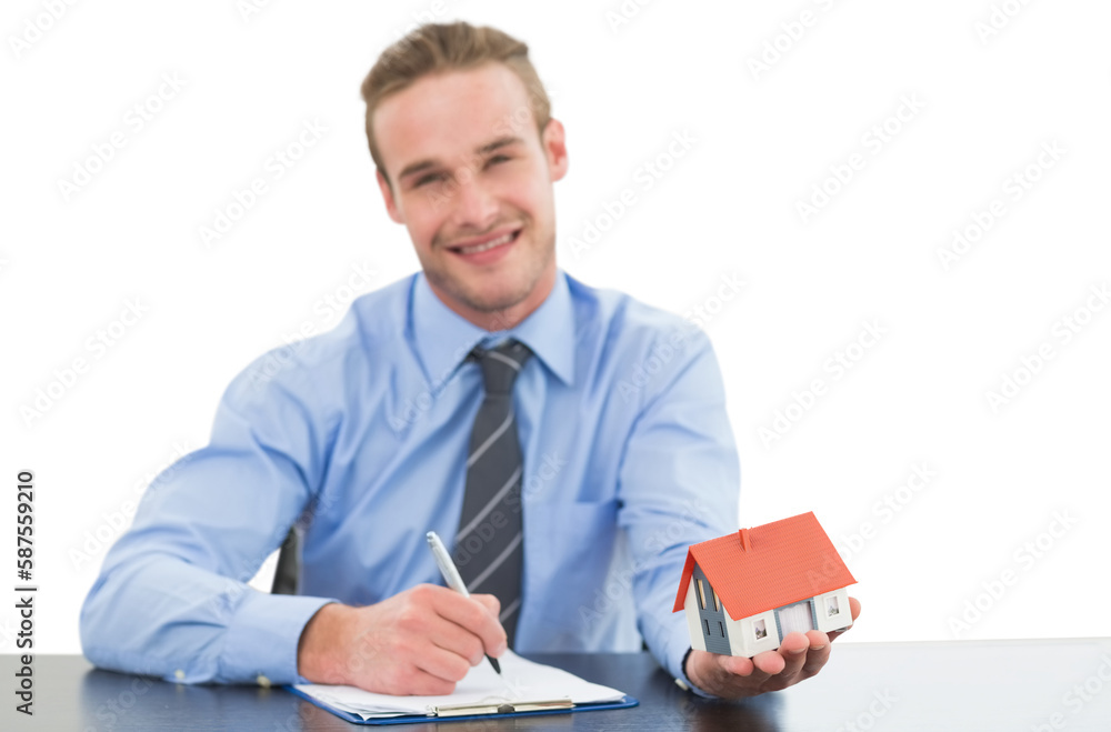 Real estate agent holding model house while writing on clipboard Real estate agent holding model house while writing on clipboard