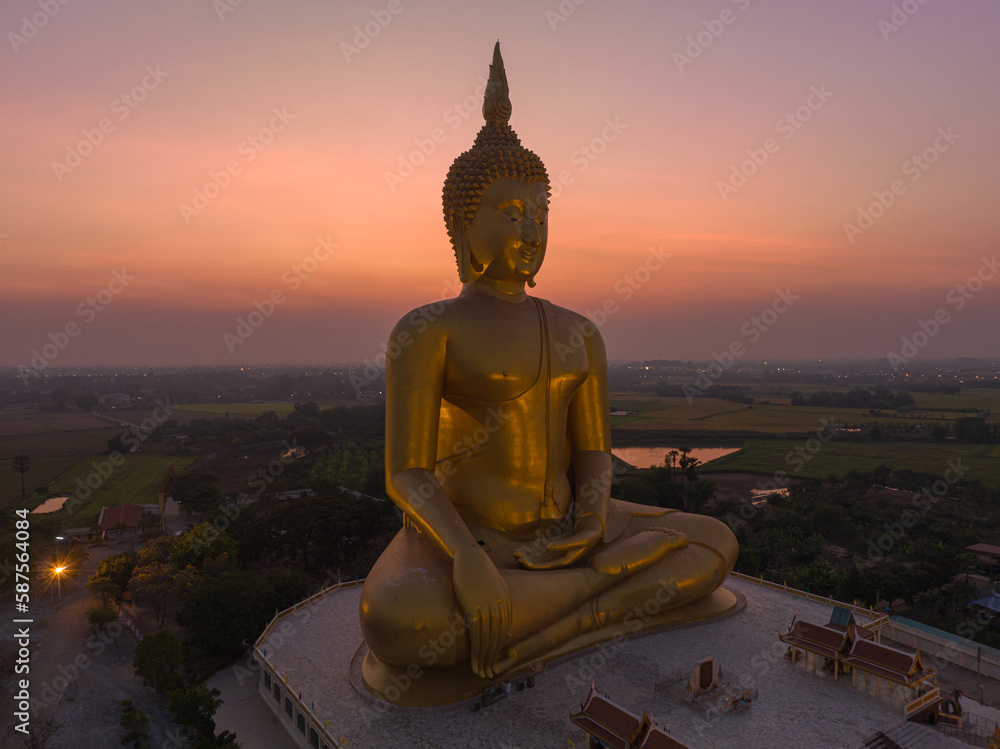 Obraz premium aerial view The moon was above the head of the biggest golden Buddha in the world..scenery red sky in twilight background. .golden big buddha is a popular landmark at wat Muang Ang Thong Thailand.