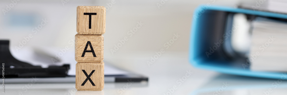 Tax text on wooden cubes on table with documents Tax text on wooden cubes on table with documents