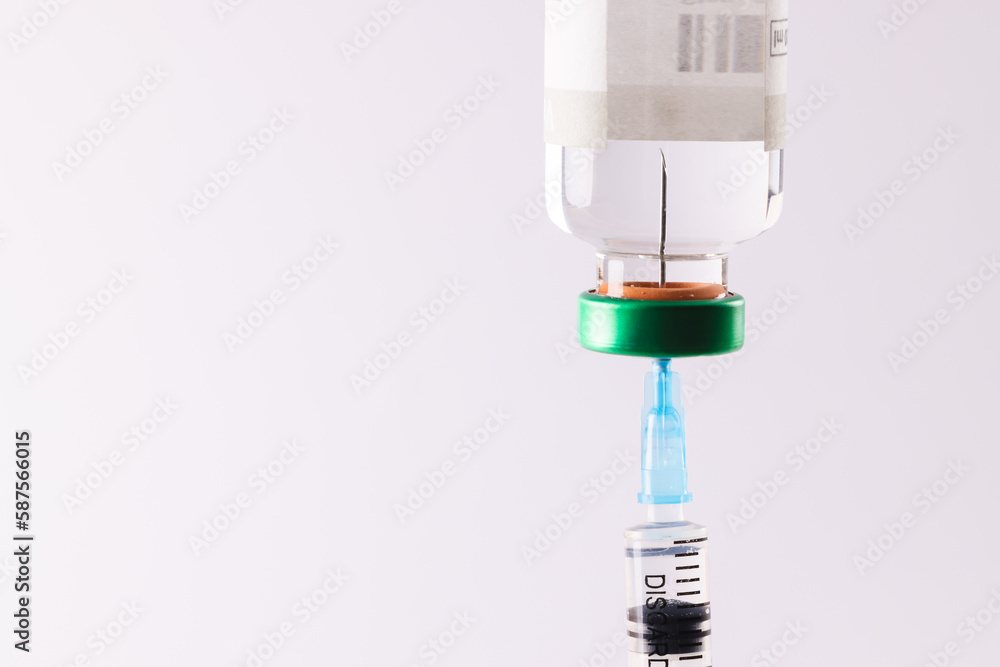 Syringe filling from vial of clear liquid such as insulin, on white background with copy space Syringe filling from vial of clear liquid such as insulin, on white background with copy space