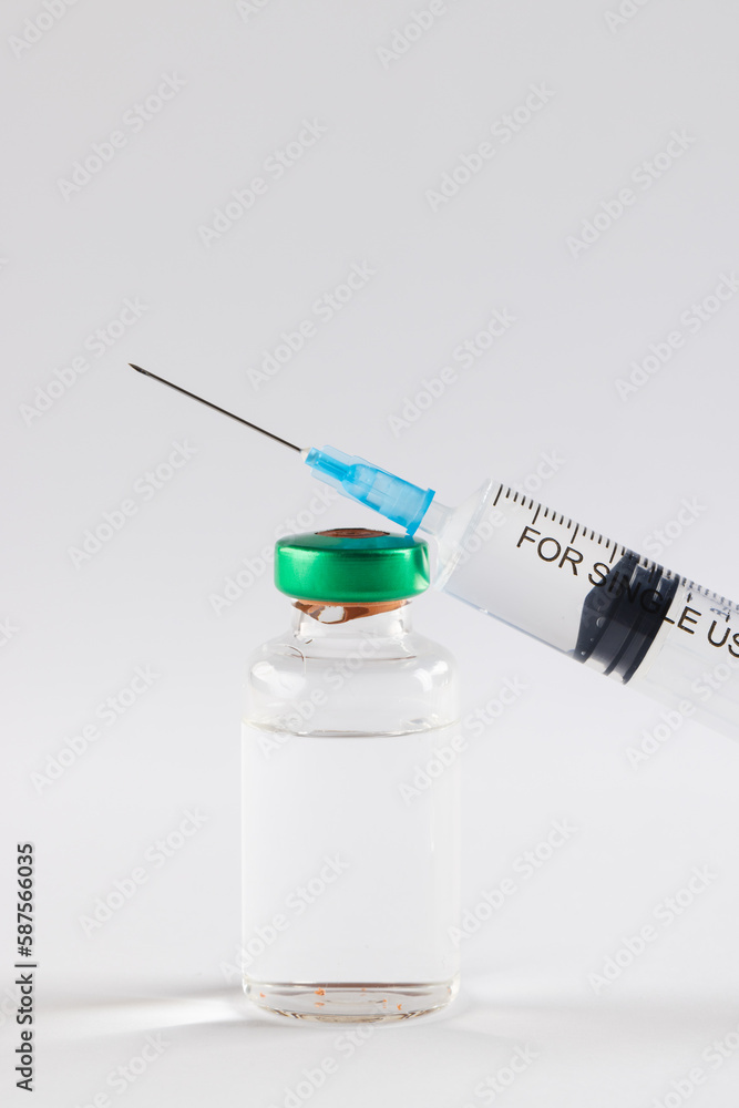 Vial of clear liquid and large syringe on white background with copy space Vial of clear liquid and large syringe on white background with copy space
