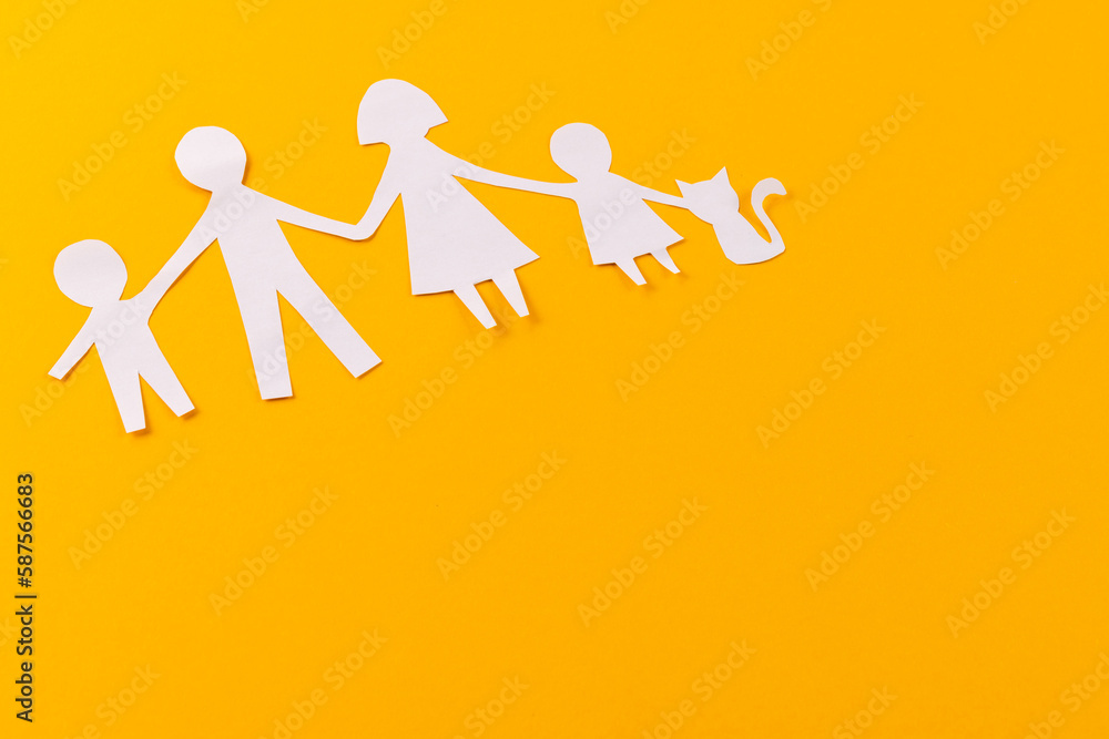 White paper cut out of family with two children and ca and copy space on orange background White paper cut out of family with two children and ca and copy space on orange background