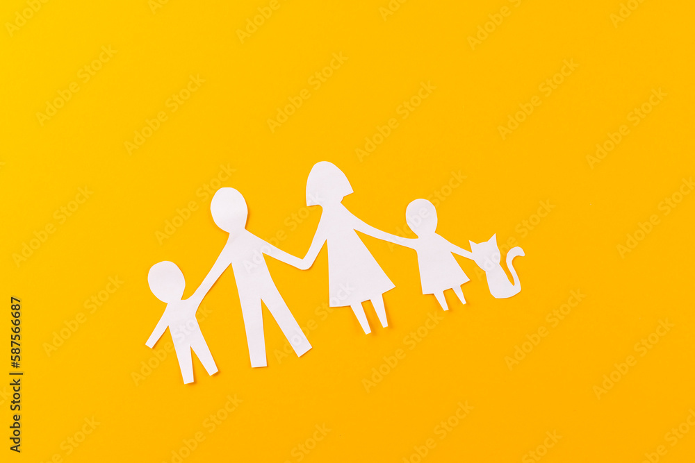 White paper cut out of family with two children and ca and copy space on orange background White paper cut out of family with two children and ca and copy space on orange background
