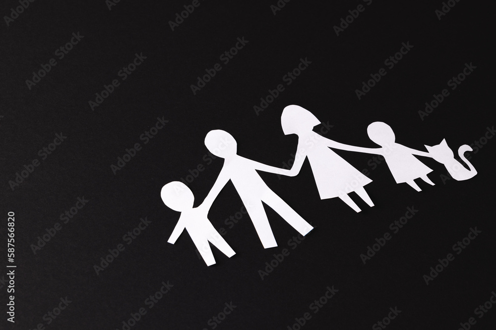 White paper cut out of family with two children and cat and copy space on black background White paper cut out of family with two children and cat and copy space on black background