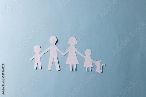 Fototapeta Naklejka Na Ścianę i Meble -  White paper cut out of family with two children and cat and copy space on blue background