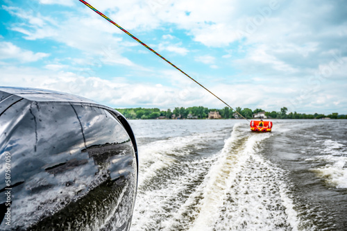 Slika na platnu Inflatable raft being pulled at a high speed by a boat in a recreational activit