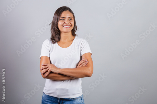 beautiful brazilian woman with arms crossed. denim and white. optimistic, smiling.