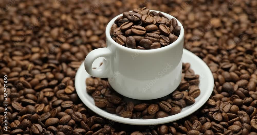 Ceramic cup full of coffee beans on a rotating background of fresh roasted coffee beans Ceramic cup full of coffee beans on a rotating background of fresh roasted coffee beans