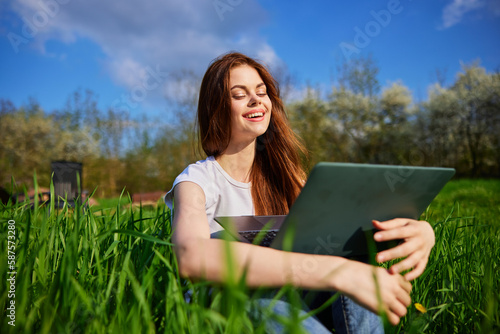 happy woman working on a laptop while on vacation in a high grass field photo