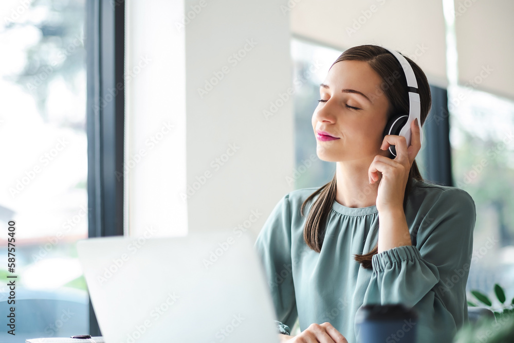 Relaxed young businesswoman in headphones enjoying music podcast using laptop app, smiling female millennial student or office worker wearing headset listening to new favorite audio tracks. Relaxed young businesswoman in headphones enjoying music podcast using laptop app, smiling female millennial student or office worker wearing headset listening to new favorite audio tracks.