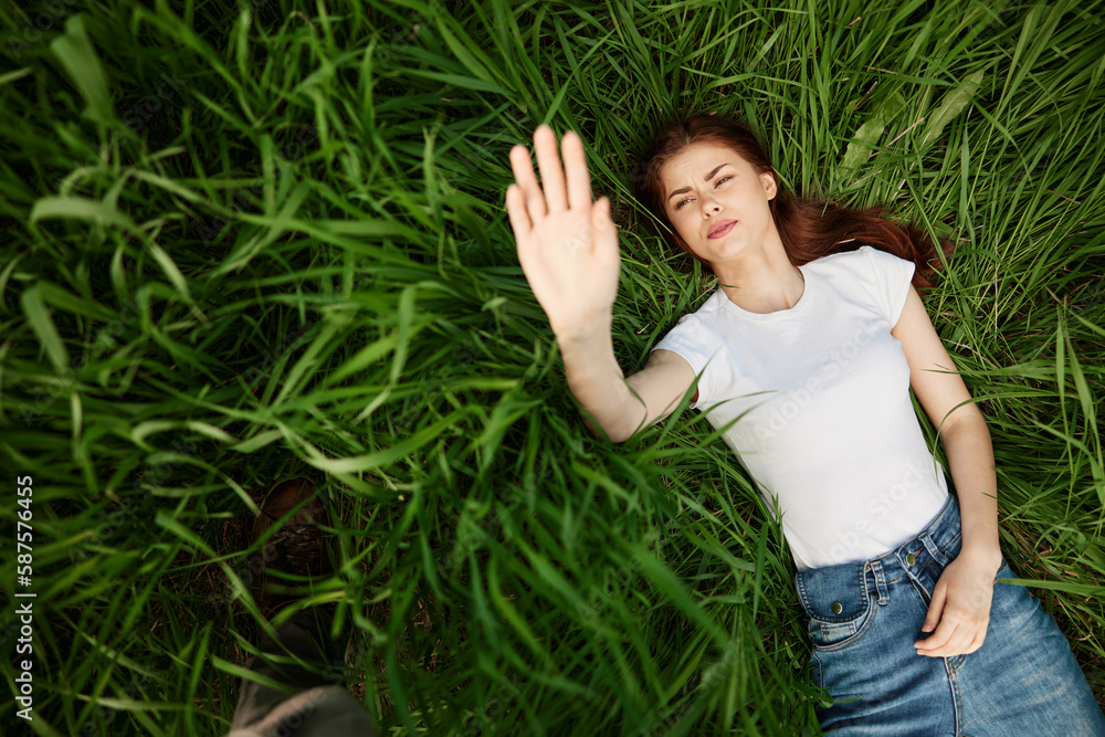 happy woman lies in high grass lit by the sun stretching her hands to the camera happy woman lies in high grass lit by the sun stretching her hands to the camera