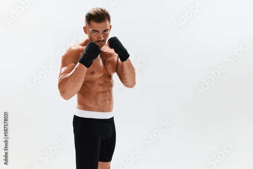 Man athletic bodybuilder poses in boxing gloves with nude torso abs in full-length background, boxing and martial arts. Advertising, sports, active lifestyle, competition, challenge concept.  © SHOTPRIME STUDIO