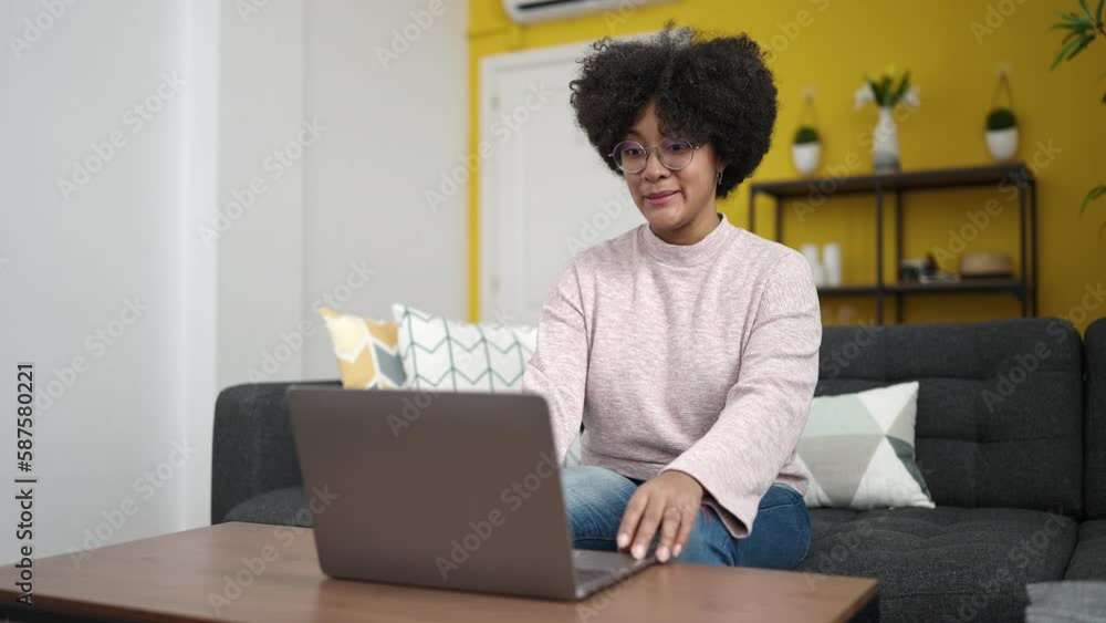 Young african american woman having video call sitting on sofa at home Young african american woman having video call sitting on sofa at home