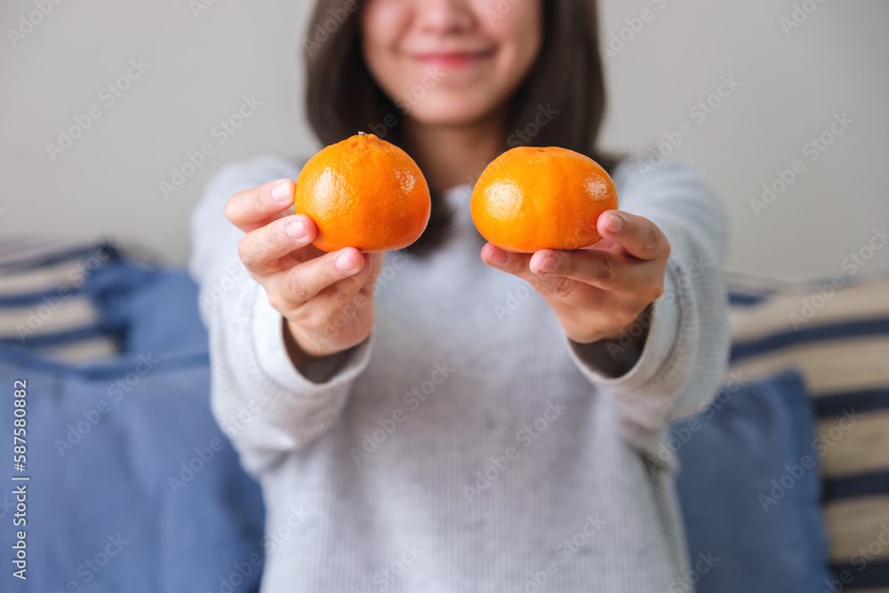 Closeup image of a young woman holding oranges in hands Closeup image of a young woman holding oranges in hands