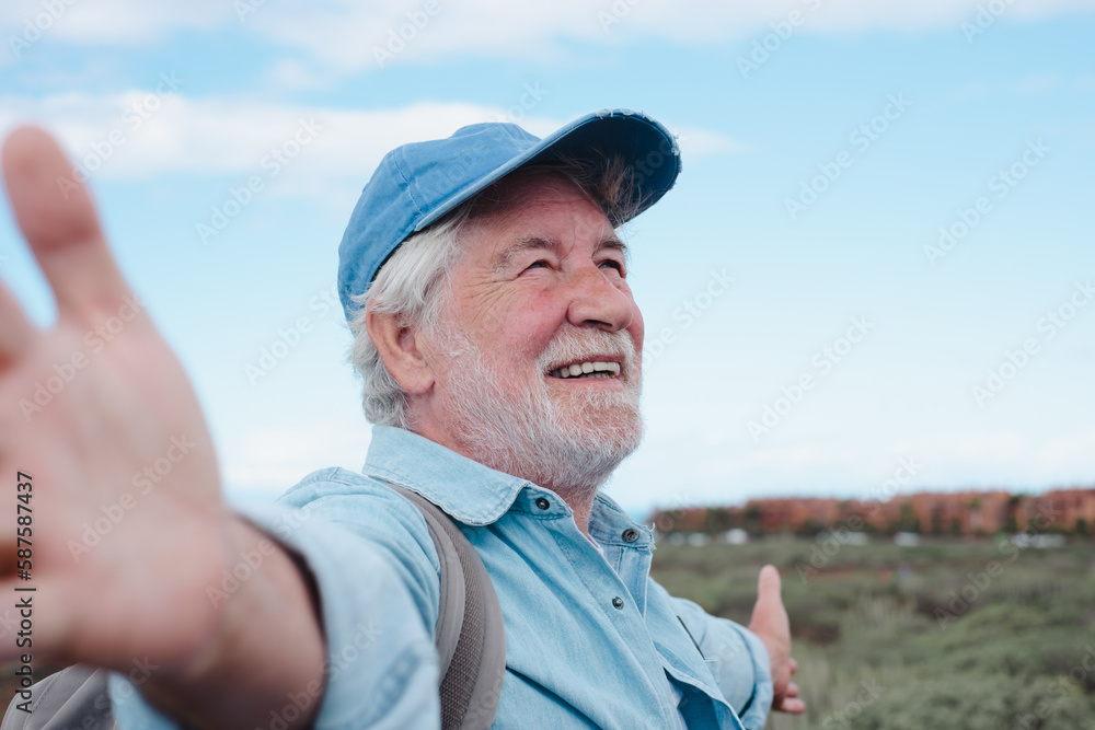 Happy senior man with hat with open arms in a trekking day in country footpath, enjoying healthy lifestyle and freedom, vacation or retirement concept Happy senior man with hat with open arms in a trekking day in country footpath, enjoying healthy lifestyle and freedom, vacation or retirement concept