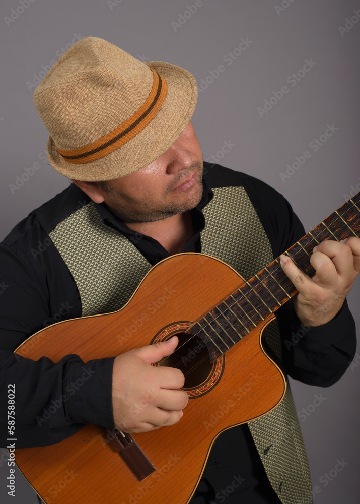 Obraz premium Studio portrait of man wearing a hat playing an old Cuban tres.