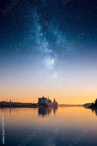 Ship in a harbor with an epic star sky above, transportation and shipping concept