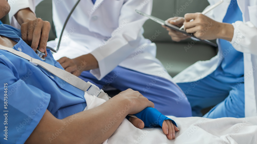 Cropped image of doctor in uniform with stethoscope using tablet standing in hospital with patient lying in bed on background Operator checks patient information on digital tablet Cropped image of doctor in uniform with stethoscope using tablet standing in hospital with patient lying in bed on background Operator checks patient information on digital tablet