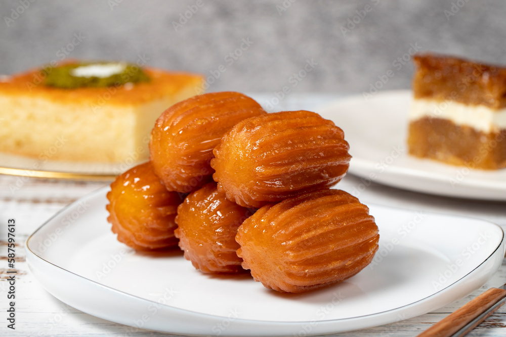 Güllaç, revani, tulumba and bread kadayif dessert with cream on a wood floor. Ramadan sweets. Traditional Turkish cuisine delicacies. Close up Güllaç, revani, tulumba and bread kadayif dessert with cream on a wood floor. Ramadan sweets. Traditional Turkish cuisine delicacies. Close up