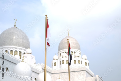 Indonesian and UAE flags with mosque dome background photo