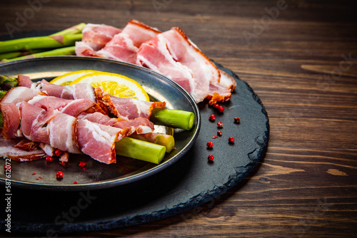 Uncooked green asparagus with prosciutto on wooden table 