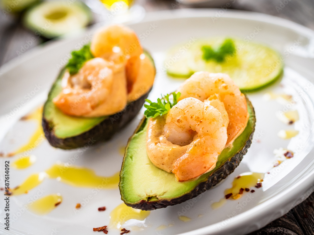 Avocado with fried prawns on and cocktail sauce on wooden background
Avocado with fried prawns on and cocktail sauce on wooden background