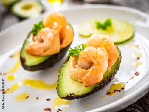 Avocado with fried prawns on and cocktail sauce on wooden background 