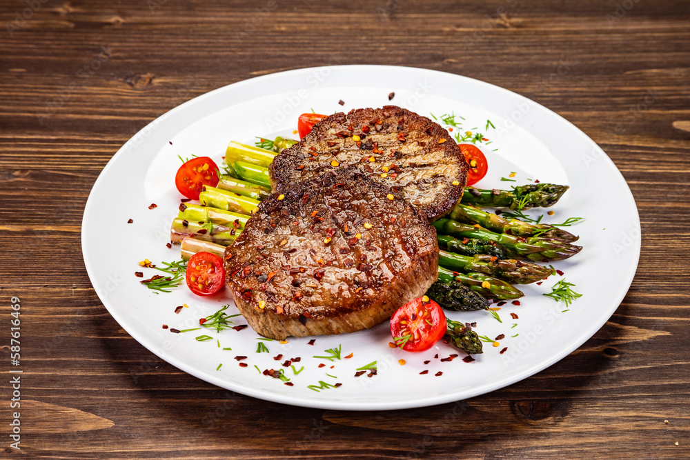 Barbecued beef steak with green asparagus on wooden table
Barbecued beef steak with green asparagus on wooden table