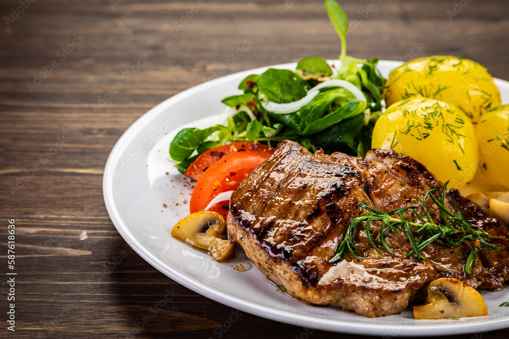 Fried beef steak with boiled potatoes and vegetables on wooden table
Fried beef steak with boiled potatoes and vegetables on wooden table
