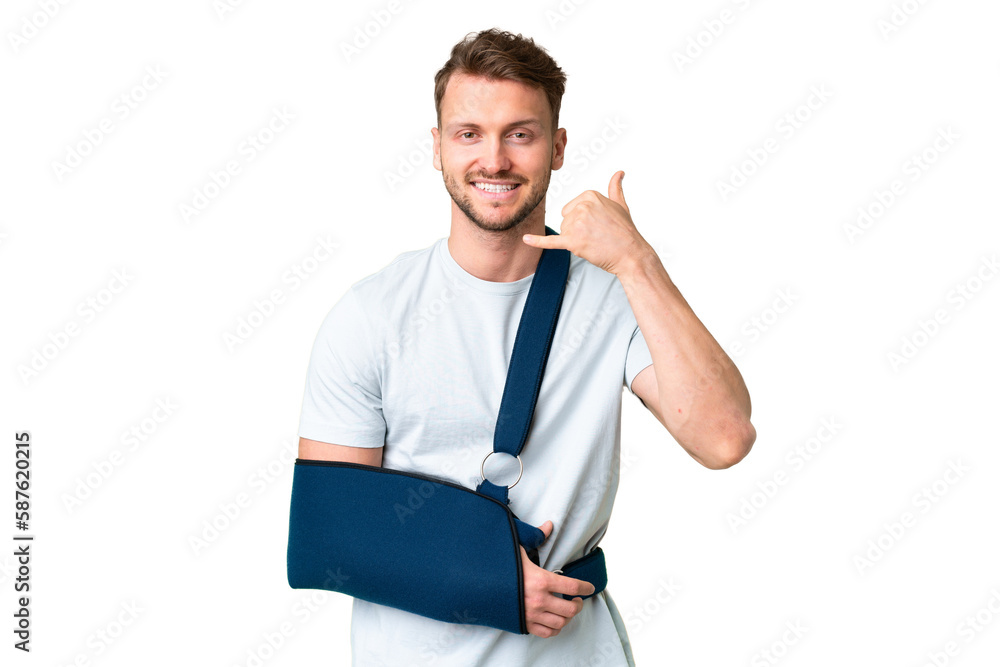Young caucasian man with broken arm and wearing a sling over isolated chroma key background making phone gesture. Call me back sign Young caucasian man with broken arm and wearing a sling over isolated chroma key background making phone gesture. Call me back sign