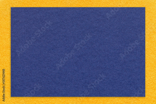 Texture of craft navy blue color paper background with yellow border, macro. Vintage dense kraft denim cardboard